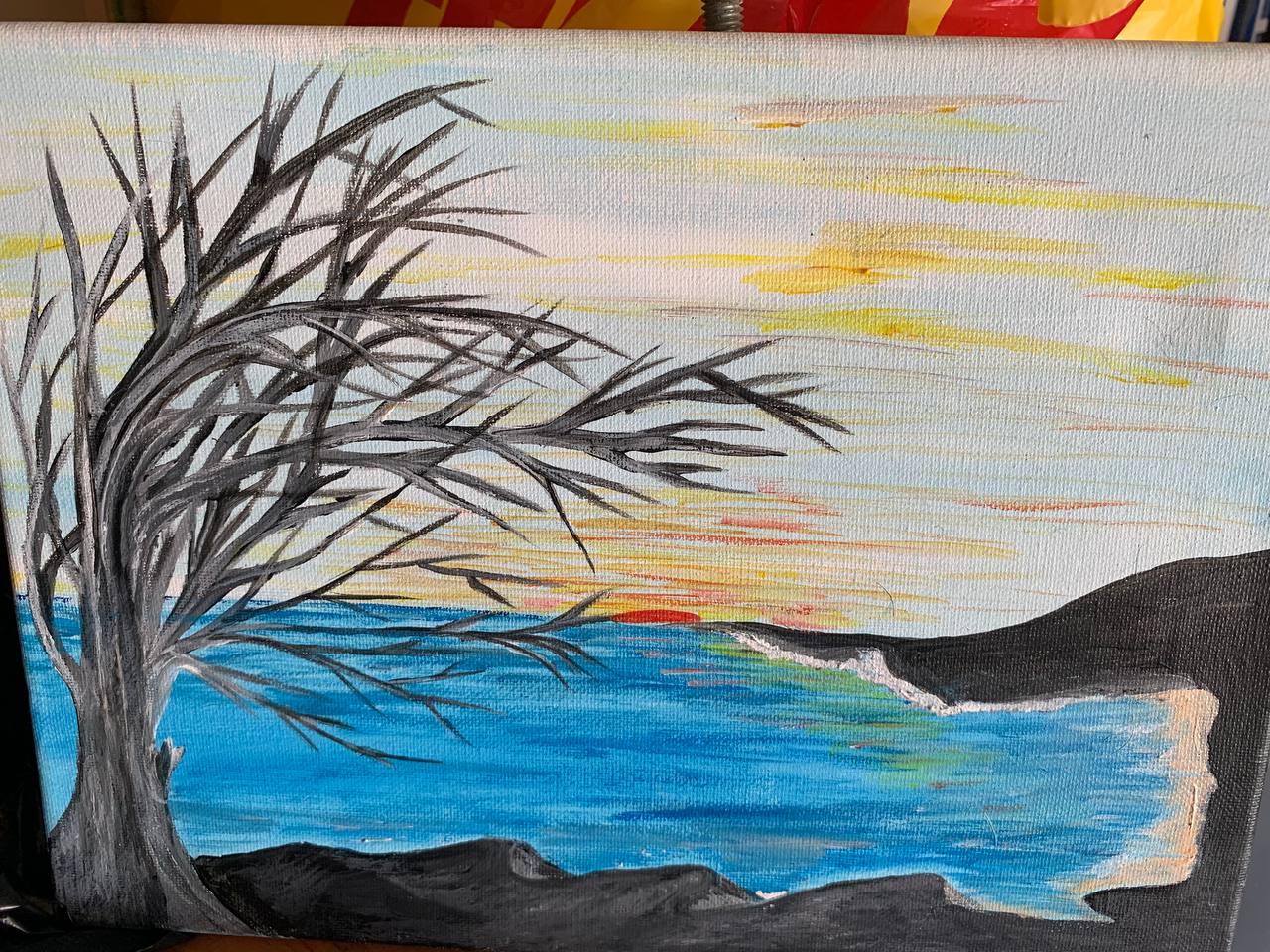 Tree by shore at sunset